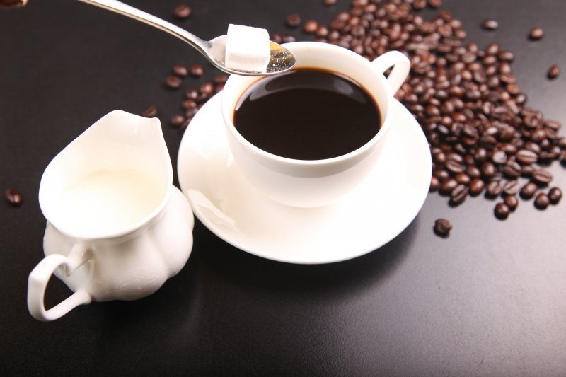 Coffee cup with a side of cream and table spoon of sugar